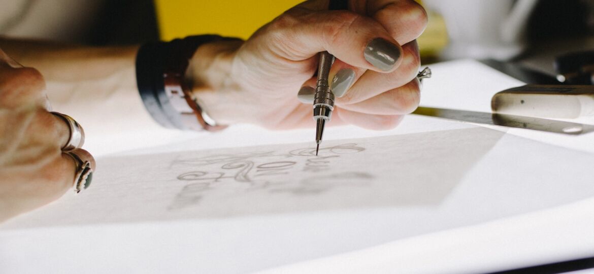 person lettering on tracing paper using mechanical pencil